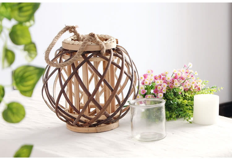 Un porte-bougie rustique en bambou tissé, avec des lanières de bambou brun foncé entrelacées, une base en bois naturel et une poignée, conçu pour la décoration intérieure du domicile.