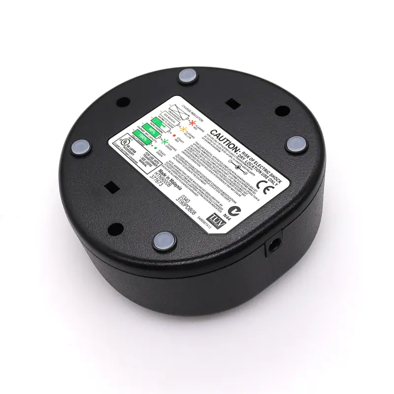 Chargeur de bureau circulaire noir pour talkie-walkie Motorola Walkie Talkie destiné au GP328 HT750, avec une étiquette blanche affichant des marquages de sécurité et de certification, fixée au moyen de quatre vis argentées sur la face arrière.