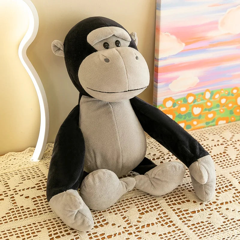 Un peluche de animal de la jungla que presenta un gorila suave en negro y gris, hecho de tela aterciopelada.