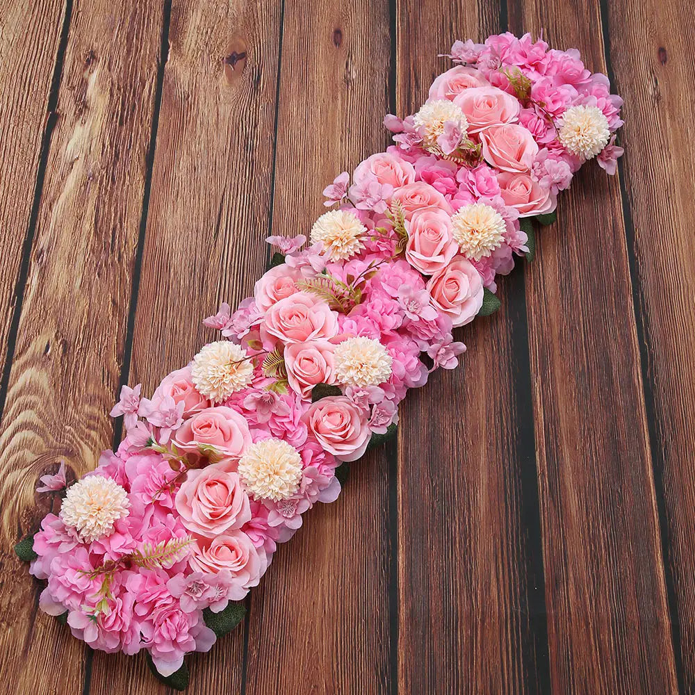 Composition de fleurs de sol pour mariage de rose blanche, présentant une délicate guirlande florale rose, avec des roses et des hortensias artificiels dans des tons pastel doux.
