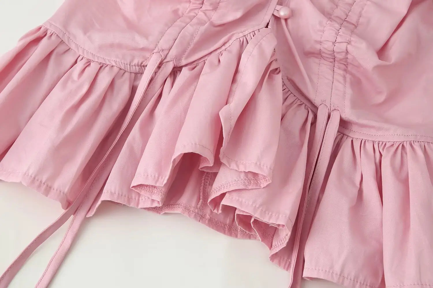 Women slim-fit long sleeve top featuring a round neckline paired with a pink ruffled dress with a corset-style bodice and lace-trimmed ties.