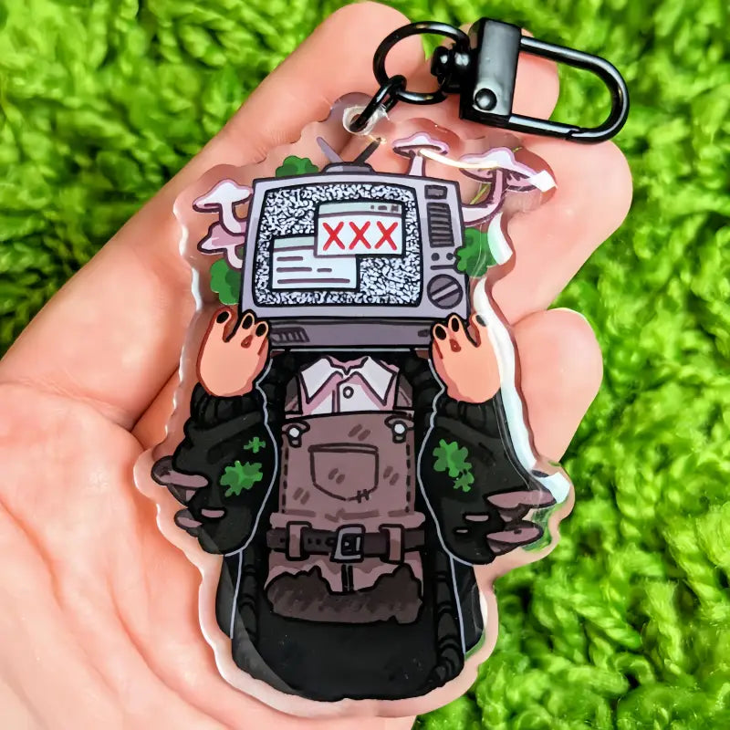 clear acrylic anime keychain featuring a cartoon character with a vintage television head displaying static and red xxx text for customizable bag charm use.