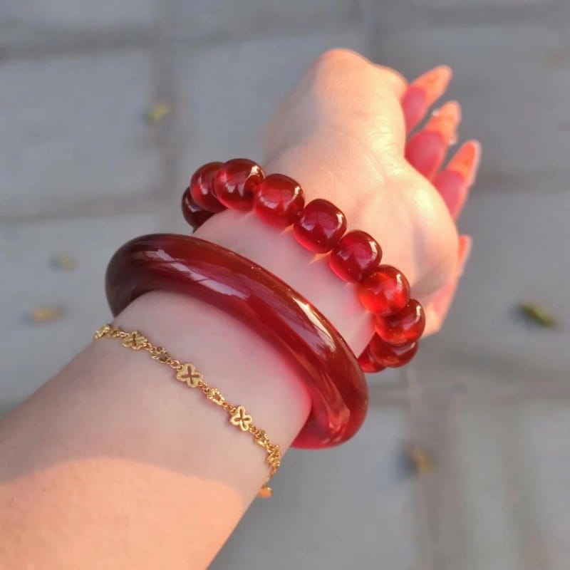 A glossy deep red jade bangle bracelet for women in a classic round style worn on a wrist.