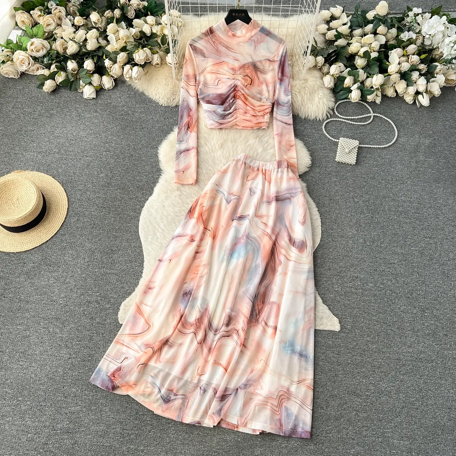 a two piece mesh skirt set featuring a flowing high neck long sleeved top and wide skirt with an abstract marble print in soft pink lavender and gray hues with elastic closure type