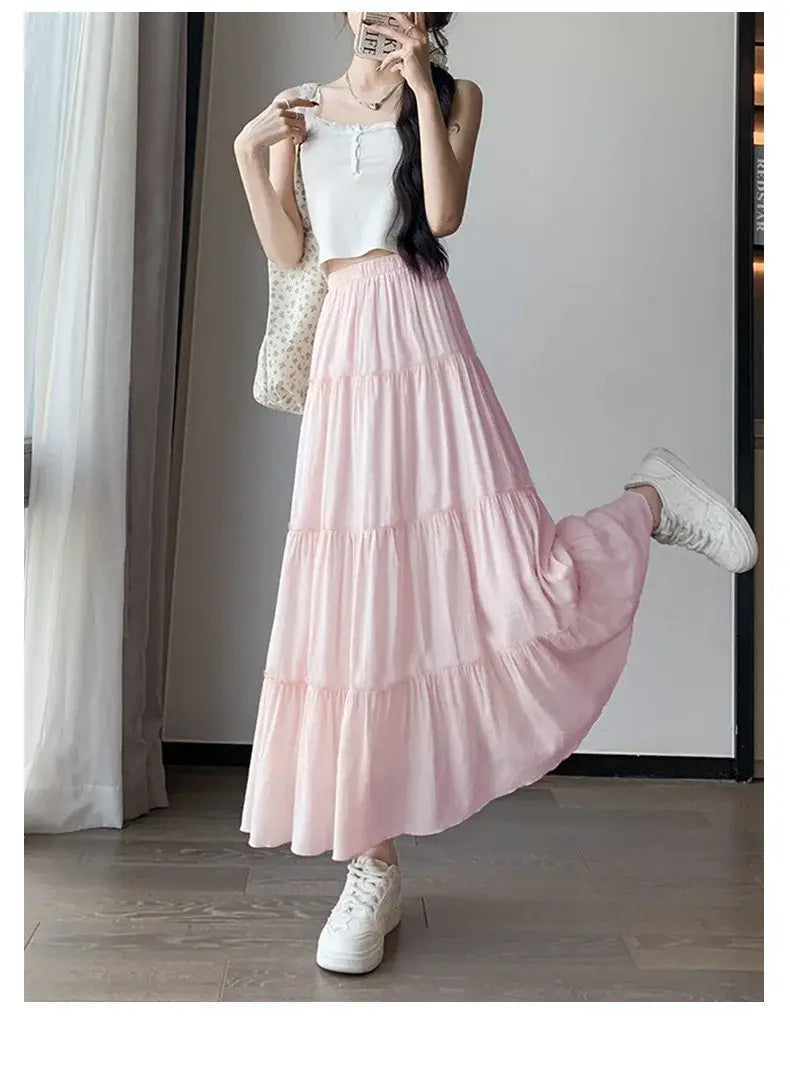 Jupe longue maxi plissée à volants superposés blanche en rose pastel, avec un tissu fluide et léger et un ourlet à volants délicat