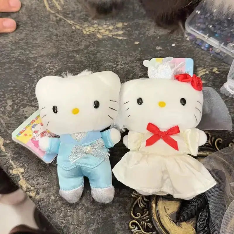 Porte-clés en peluche couple de mariage Hello Kitty blanche, représentant une figurine en costume bleu clair avec des accents argentés et l’autre en robe de mariée avec un nœud rouge.