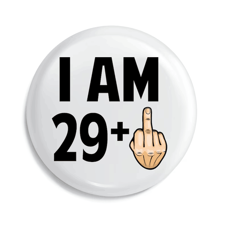 badge de broche émaillé circulaire blanc avec du texte noir indiquant « j’ai 29 ans et plus » et une main dessinée faisant un doigt d’honneur, conçu comme un cadeau amusant d’anniversaire marquant une étape d’âge.