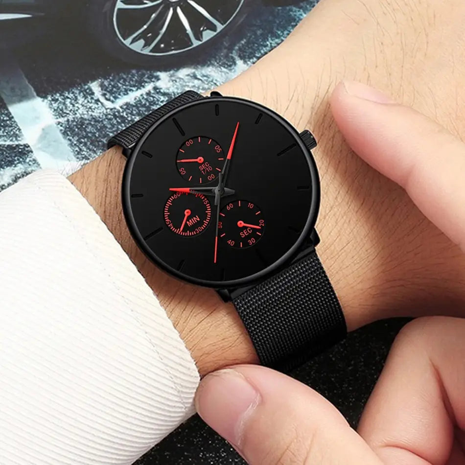 Montre à quartz à maille noire ultrafine pour hommes, avec un cadran chronographe noir, des aiguilles rouges et des sous-cadrans, ainsi qu’une sangle en maille.