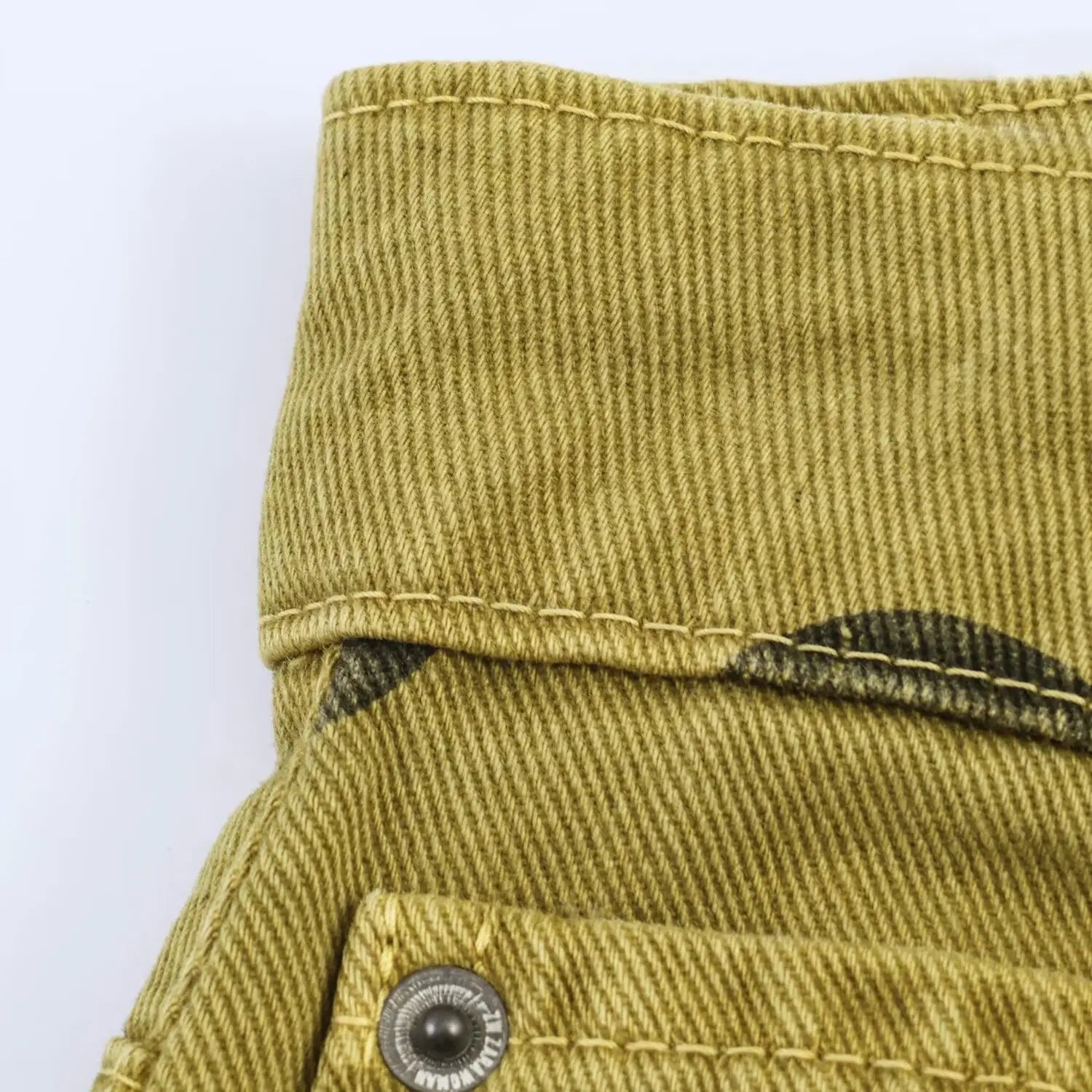 Olivgrüne Cordhose mit weitem Bein, mit dezentem diagonalem Rippenmuster und kontrastierender dunkler Ziernähte