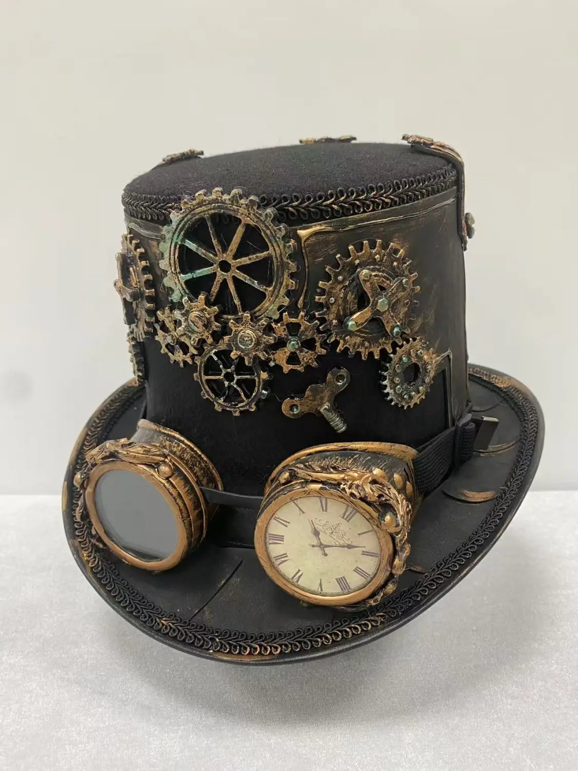 Black steampunk top hat with goggles adorned with brass and copper gears and a vintage clock face for costume or fashion use.