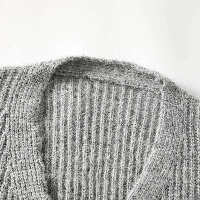 Ein Herren-V-Ausschnitt-Strickcardigan aus weichem, hellem grauem geripptem Strickmaterial mit gemütlicher, flauschiger Textur.