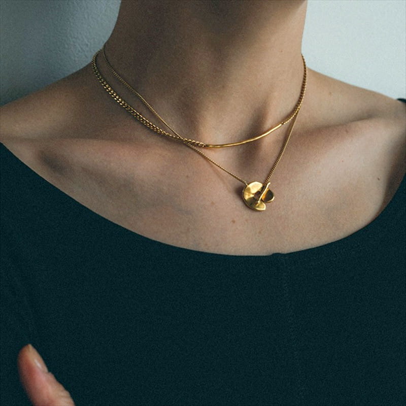 Collier pendentif à superposition géométrique doré pour femmes, présentant des chaînettes délicates aux tons dorés et un pendentif circulaire plat avec un motif gravé.