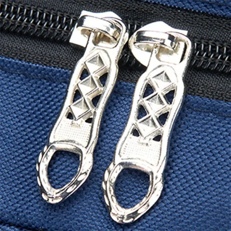 Silberfarbene Reißverschluss-Schieber mit geometrischem, dreieckigem Gitterdesign und texturierter Griffzone an einem navyblauen Jungen-Wasserschulrucksack mit Buchfach-Tasche.