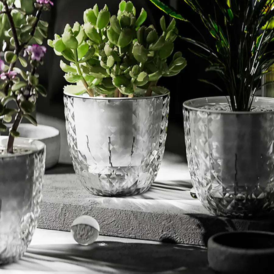 Jardinera doble de vidrio facetado transparente con patrón de corte tipo diamante y una función de riego automático para flores y plantas.