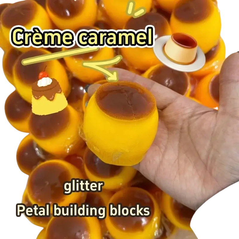 Un dulce antiestrés de pudín de caramelo amarillo y marrón con brillo, con forma de bloque de construcción tipo pétalo temático de crème caramel, se muestra desde la parte frontal.