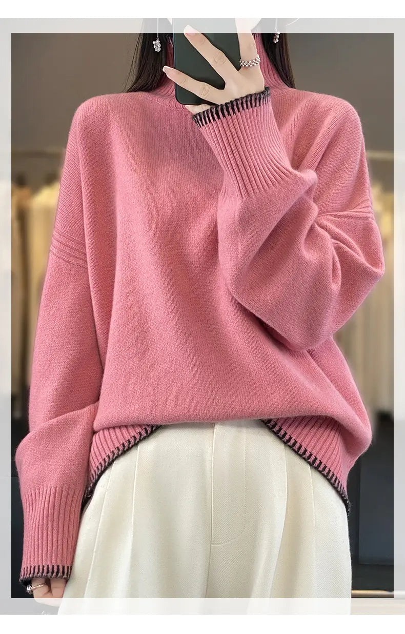 Soft pink pure wool turtleneck sweater for women with oversized knit design and ribbed cuffs and hem accented by black trim.