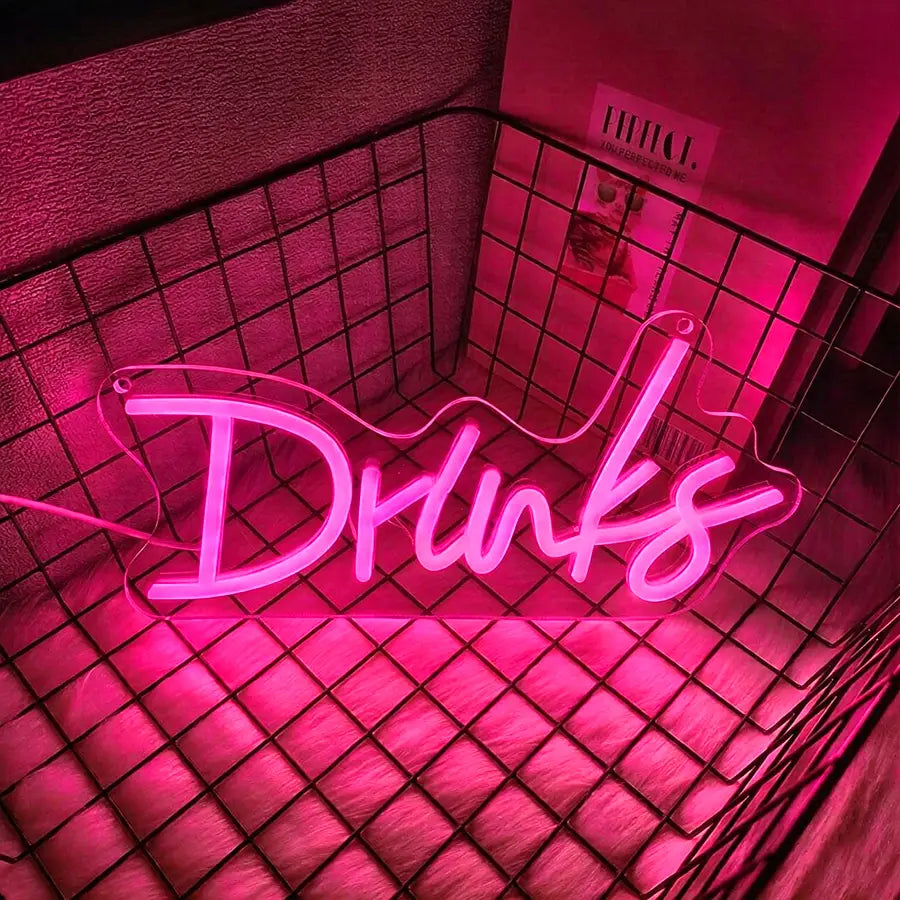 une enseigne au néon rose lumineuse affichant le mot « drinks » dans une écriture cursive, conçue comme décoration murale à LED pour un usage intérieur