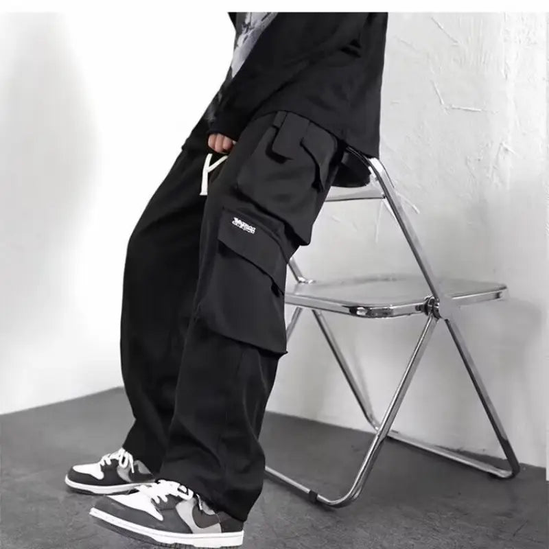 Herren-Cargo-Jogginghosen mit weitem Schnitt, Y2K-Trackpants in Schwarz, mit mehreren Taschen und einem dezenten weißen Logo auf der Obersatztasche.