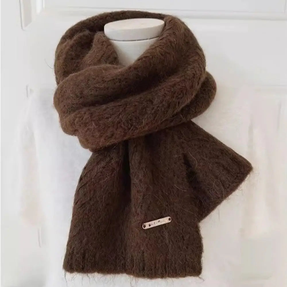 Una bufanda gruesa de punto para invierno para mujer marrón, esponjosa y cálida, con textura suave y esponjosa y una pequeña etiqueta metálica, diseñada para aportar abrigo como chal calentador de cuello.