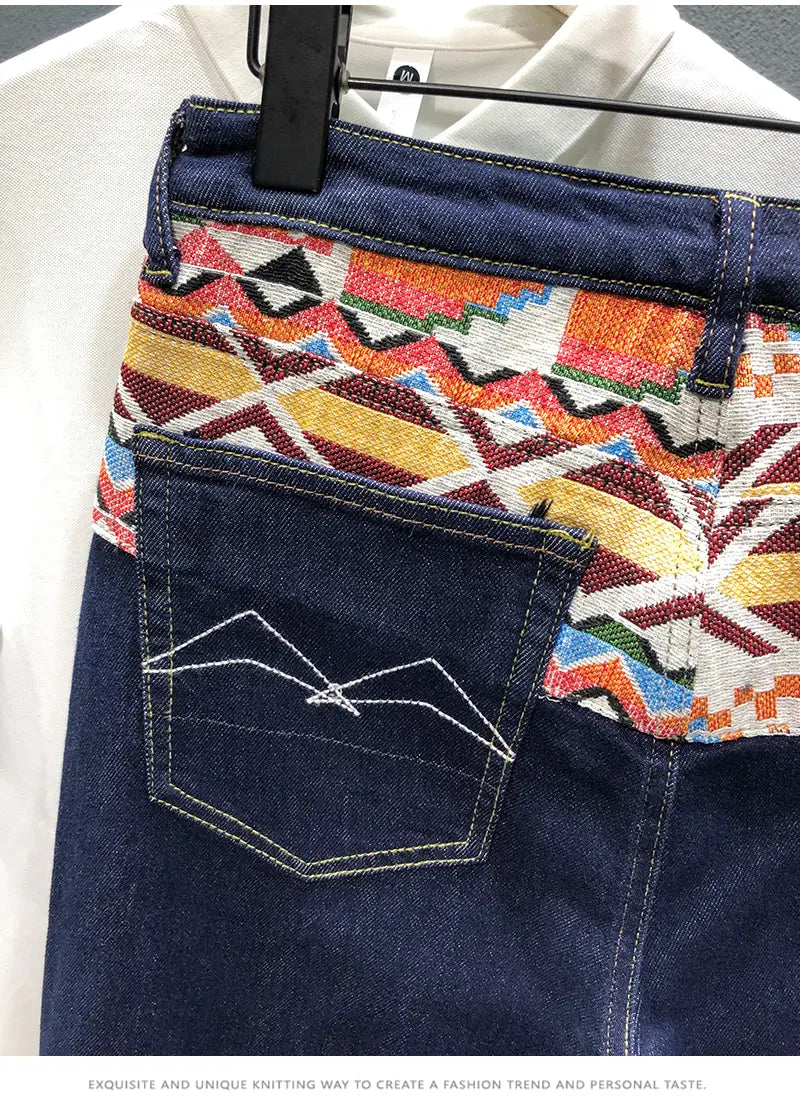 men slim fit stretch embroidered white denim jeans featuring a vibrant geometric-patterned fabric panel in orange yellow red and blue along the waistband
