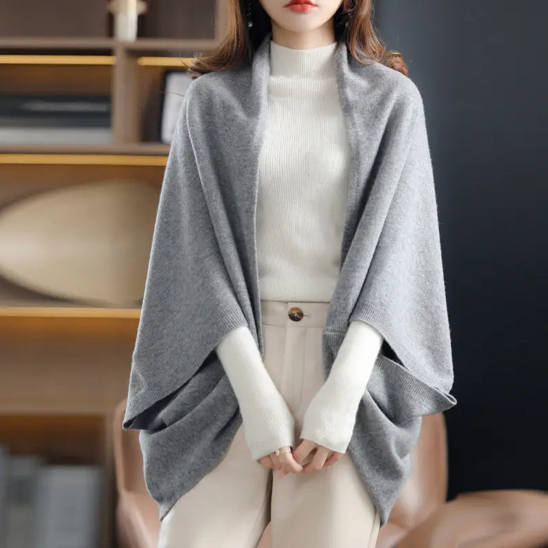 Weicher hellgrauer Kaschmir-Poncho mit drapiertem offenem Vorderseiten-Design, dargestellt als Strickschal, Cardigan oder Wickel aus Wolle.