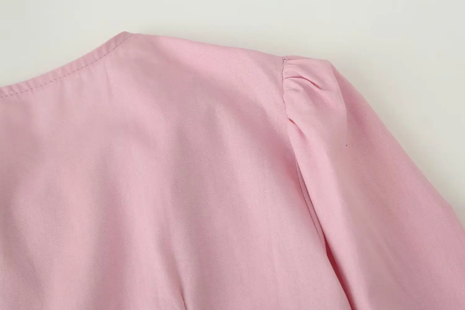 Soft pink women slim-fit long sleeve round neck top with gentle puff sleeves and neat stitching along the neckline.