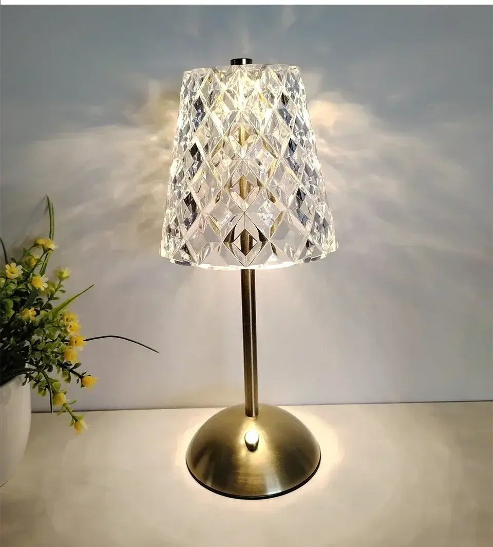 Eine wiederaufladbare Tischlampe mit einem kristallgeschnittenen Glasschirm und einer Messingbasis, beleuchtet als warme Lichtquelle