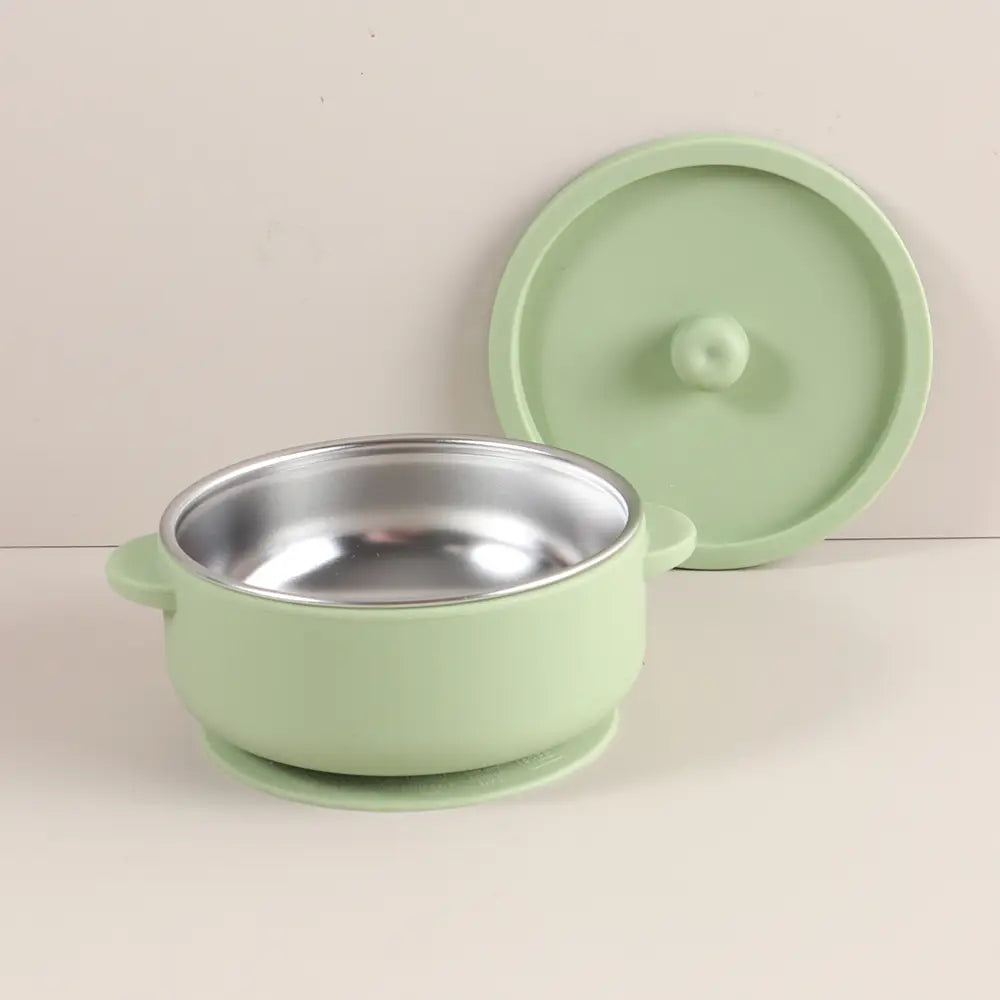 Minzgrüne Baby-Trainingsschüssel aus Silikon mit Edelstahlinnenbereich und passendem Deckel, konzipiert für das Zufüttern und die Babystillung bzw. -fütterung.