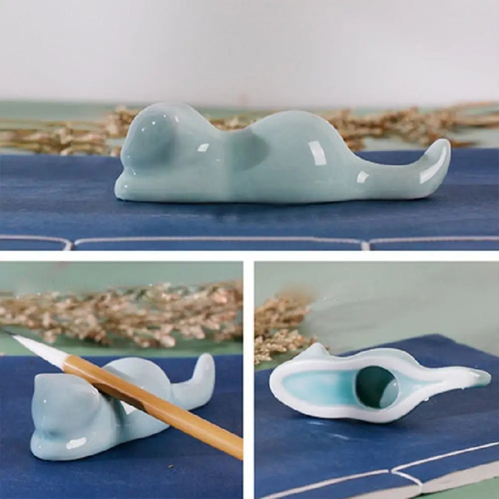 A smooth light blue ceramic pen holder shaped like a cat with a glossy finish and an open interior for holding calligraphy brushes.