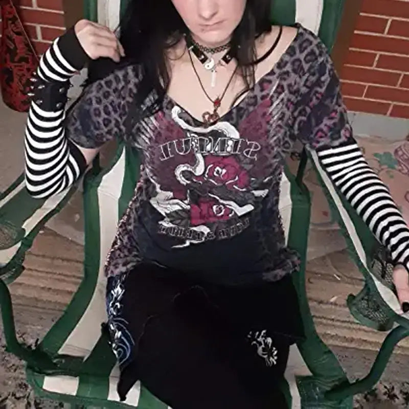 Black and gray leopard print long-sleeved top with red roses and white snakes graphic worn over black striped knit fingerless arm warmers.