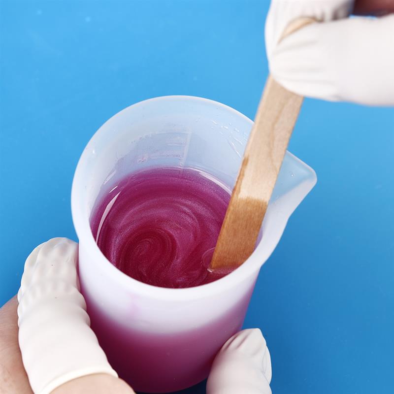 White plastic measuring cup filled with swirling purple resin mixture from epoxy resin mixing tool set for diy jewelry making.