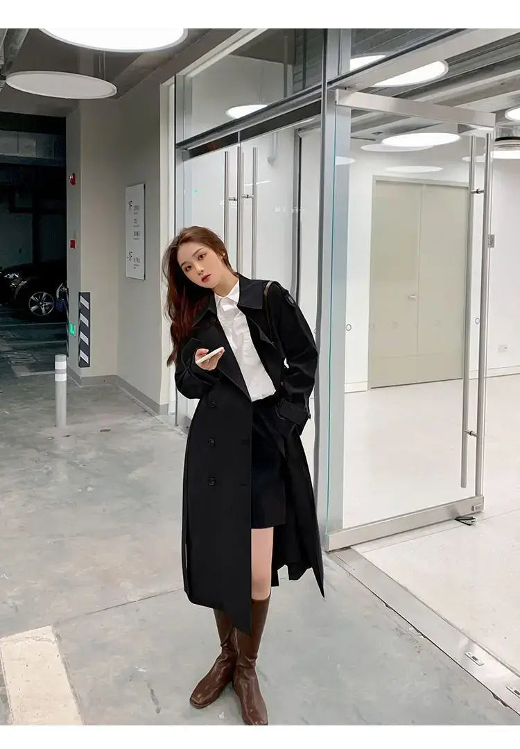 Black women double-breasted trench coat with long sleeves and a casual windbreaker style.