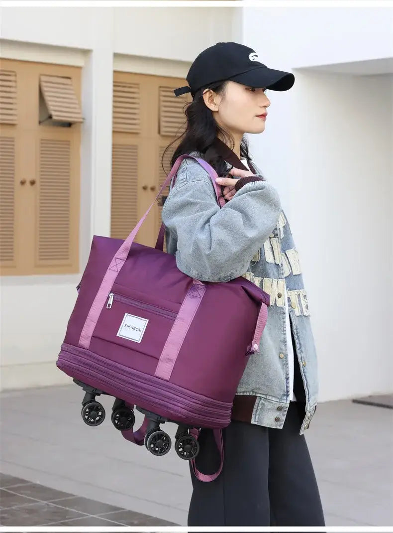 Un sac duffel roulant violet à grande capacité, avec des sangles roses et des roues noires pour un usage en voyage