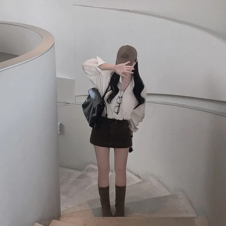 black patent leather crossbody bag with structured rectangular shape and visible zipper closure paired with a striped long sleeve button down shirt featuring versatile style and standard thickness fabric
