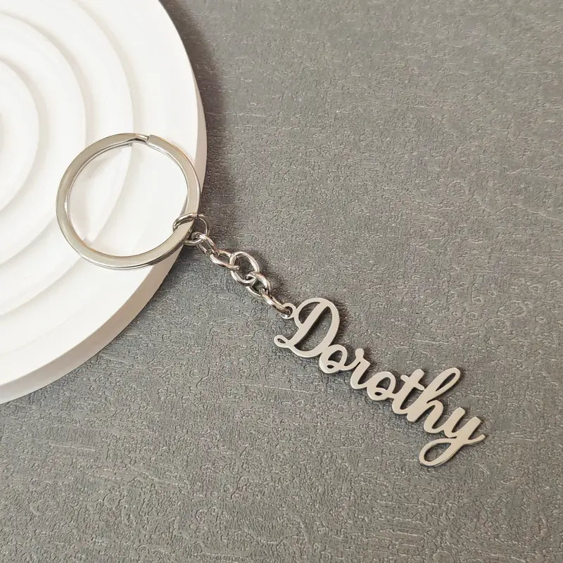 Silver metallic customized name keychain set featuring a keychain with the name Dorothy engraved in elegant cursive script attached to a circular ring by a short chain.