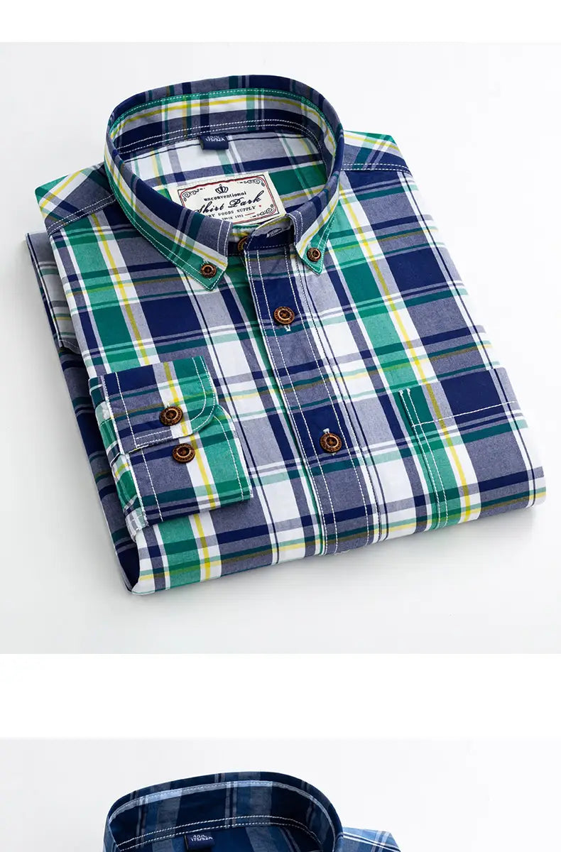 A neatly folded men’s cotton plaid long sleeve slim fit shirt with navy blue and green intersecting stripes, white accents, classic collar, and brown wooden buttons.