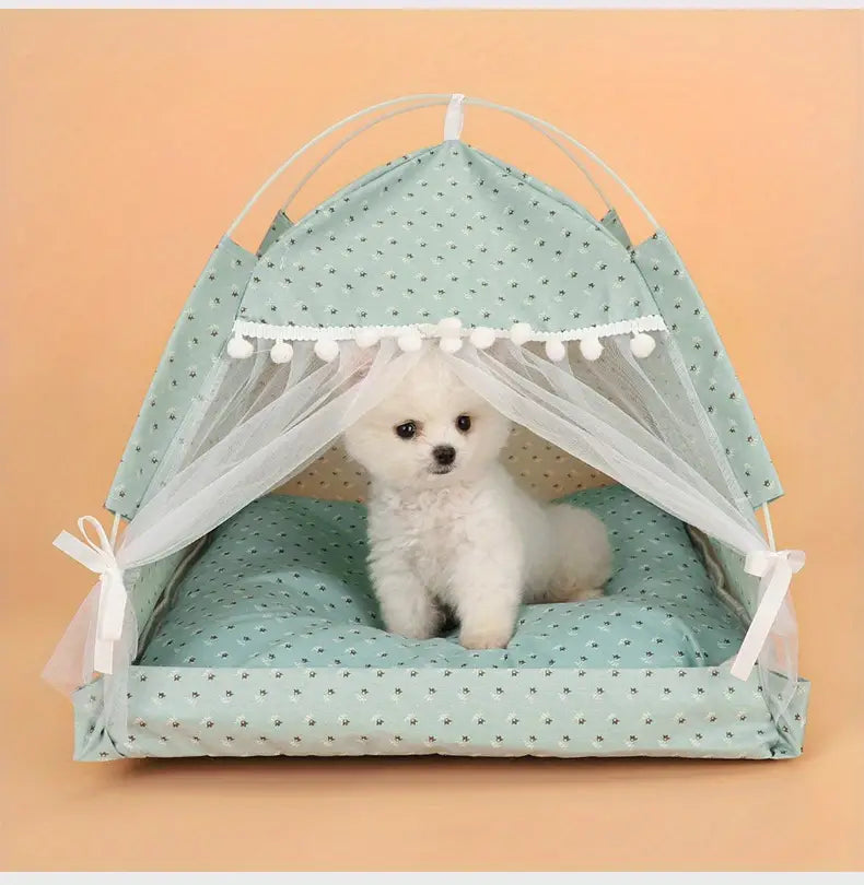 A mint green polka-dotted pet tent with white pom-pom trim and sheer mesh sides designed as a floral print cave bed for cats and dogs.
