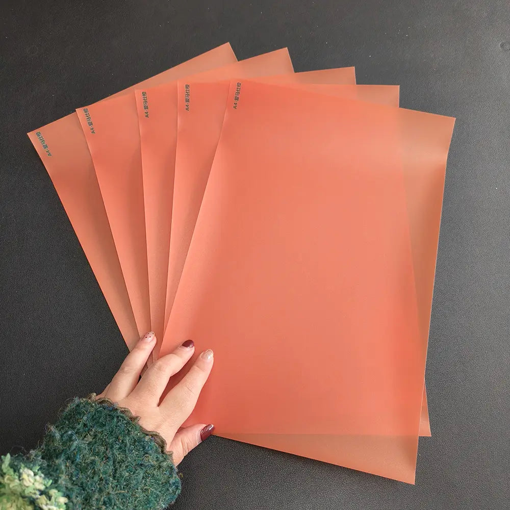 Juego de fundas para documentos de plástico translúcido color naranja, rotuladas A4 con caracteres chinos para indicar el tamaño, mostrado junto con una máquina de laminación al vacío de película para teléfonos móviles, destacando la eficiencia en la laminación al vacío de película y del costo de envío.