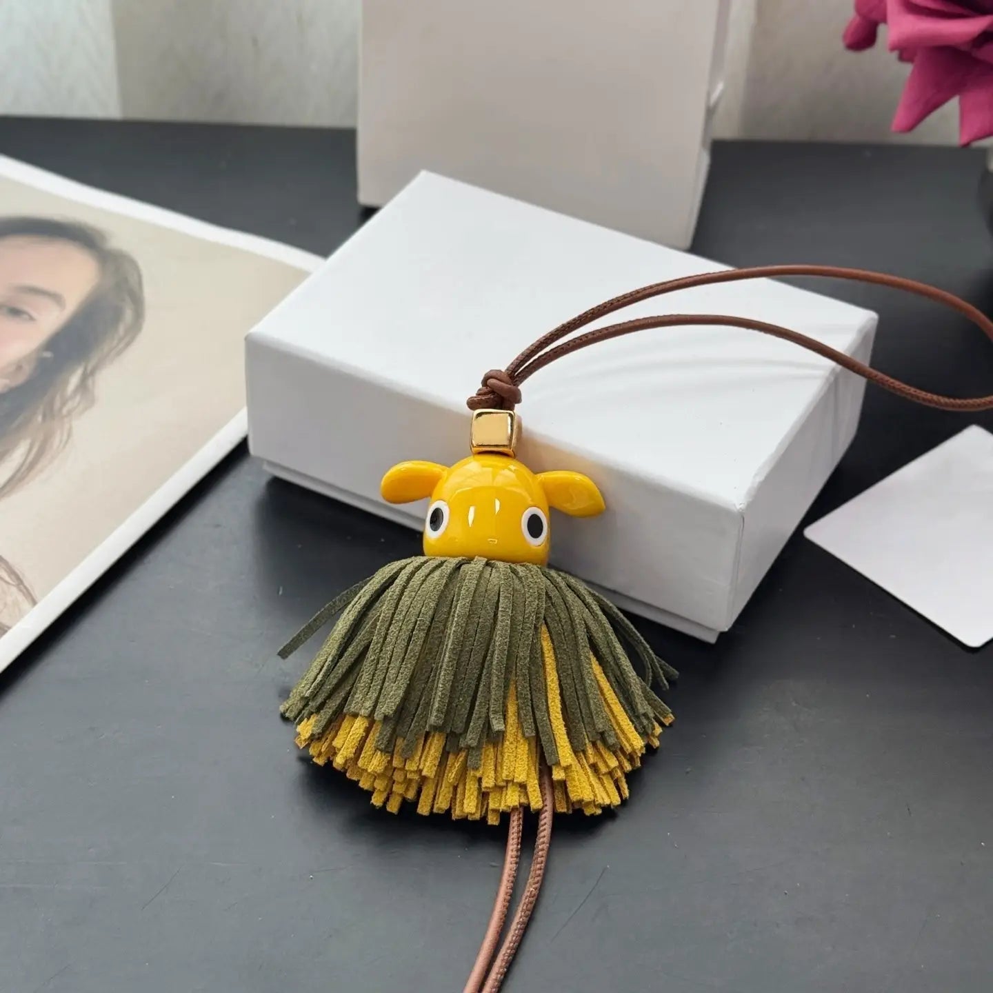 Llavero colgante para bolso con encanto de animales de cuero con un fleco de cerámica amarillo con un tierno rostro de animal y fleco de gamuza en capas verde y amarillo.