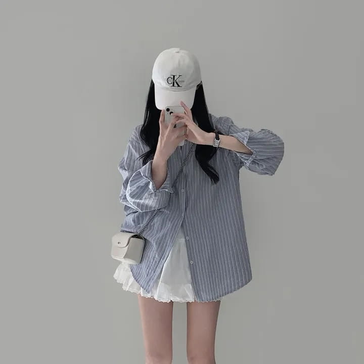 white chain-strap crossbody bag with a compact rectangular body and minimalist design paired with a versatile style striped long sleeve button down shirt of standard thickness