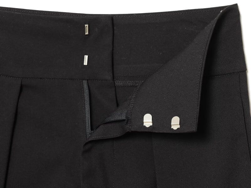 Pantalons noirs taille haute plissés à jambes évasées, au design sur mesure épuré, avec des boutons métalliques ton argenté à la ceinture