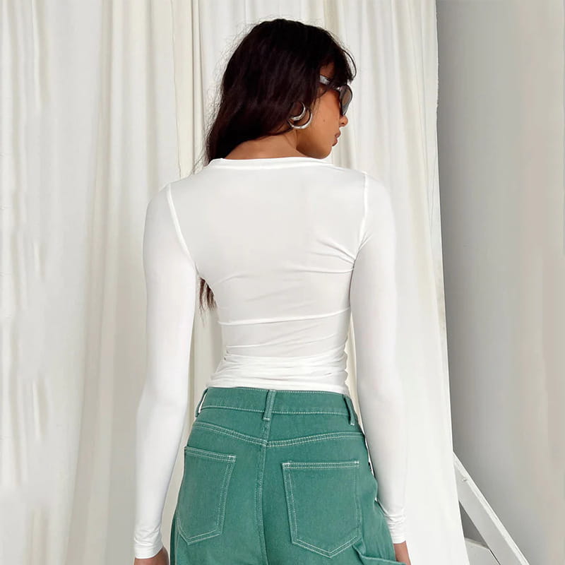 Blusa corta ajustada tipo slim fit blanca para mujer, con mangas largas fruncidas, confeccionada con material entallado y cuello redondo, mostrada desde el lado posterior.