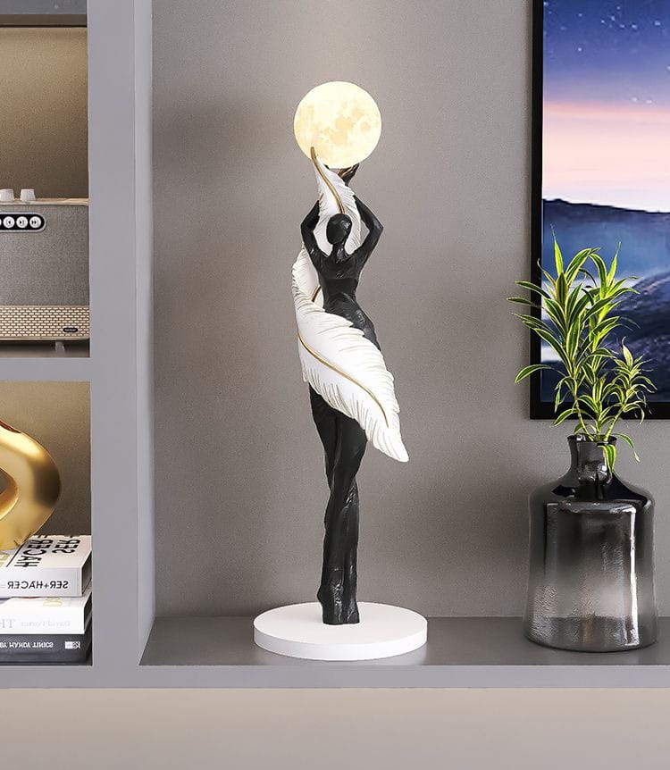 Figurine en résine de danseuse 12x12x40 cm, sculpture noir et blanc d'une femme aux ailes fluides en forme de plumes tenant une lune lumineuse, pour une décoration intérieure moderne et des effets d'exposition.