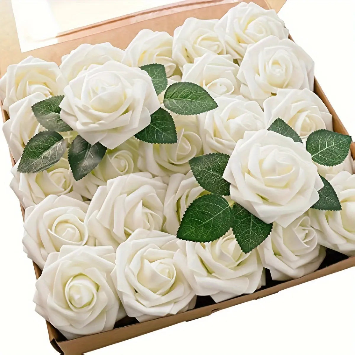 Une boîte de roses de fleurs artificielles blanches, avec des feuilles vertes et des tiges, pour la décoration.