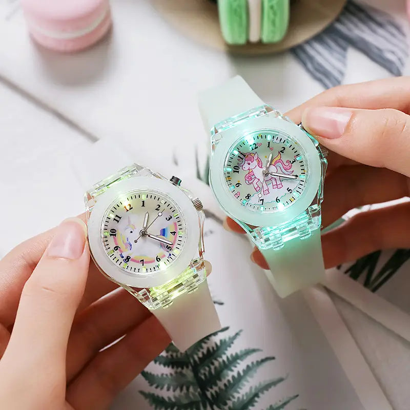 Two translucent glowing kids unicorn led light up silicone digital watches with unicorn designs on the faces and soft silicone straps.