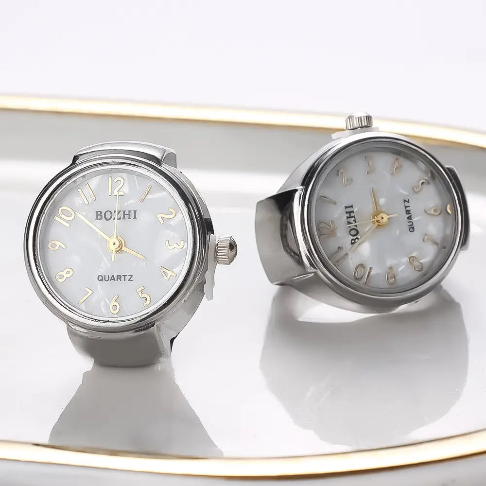 Silver-toned bozhi quartz ring watch with mother-of-pearl face and gold-tone numerals designed as a flexible unisex ring-style bracelet for gift purposes.