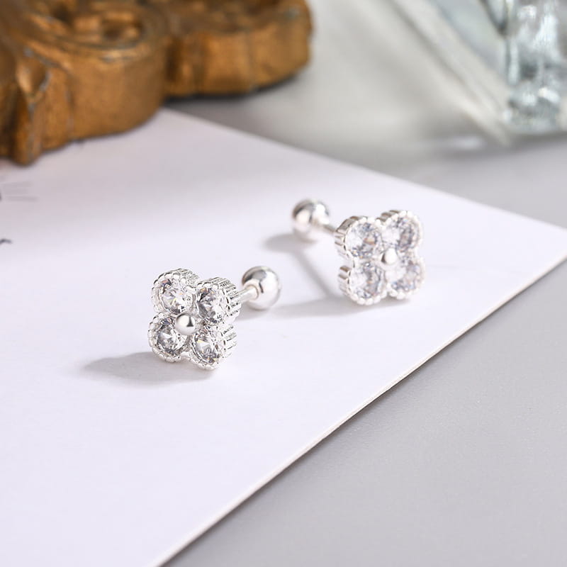 Pendientes tipo clavo de flor de cuatro piedras en plata de ley, con diseño plateado de cuatro pétalos y piedras de circonita cúbica transparentes.