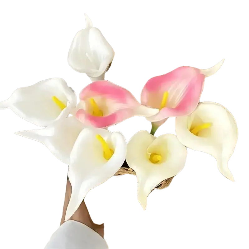 A flower bouquet of white and soft pink calla lilies with yellow centers arranged in a woven wicker basket