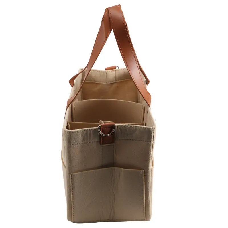 Beige canvas felt baby diaper caddy nursery storage basket with tan leather handles and a front pocket for organization.