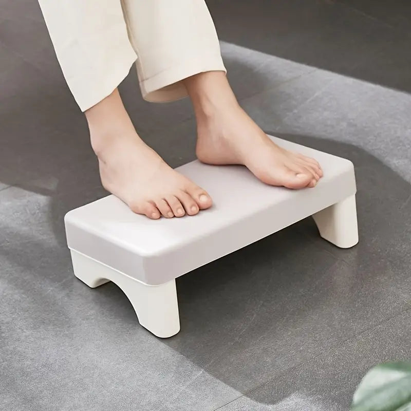 A sleek off-white ergonomic under desk plastic footrest with a minimalist rectangular design and sturdy slightly curved legs.